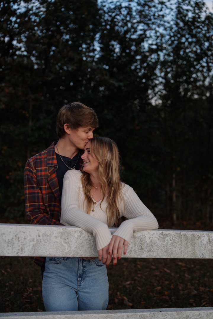 Couple close together at a fence at dusk