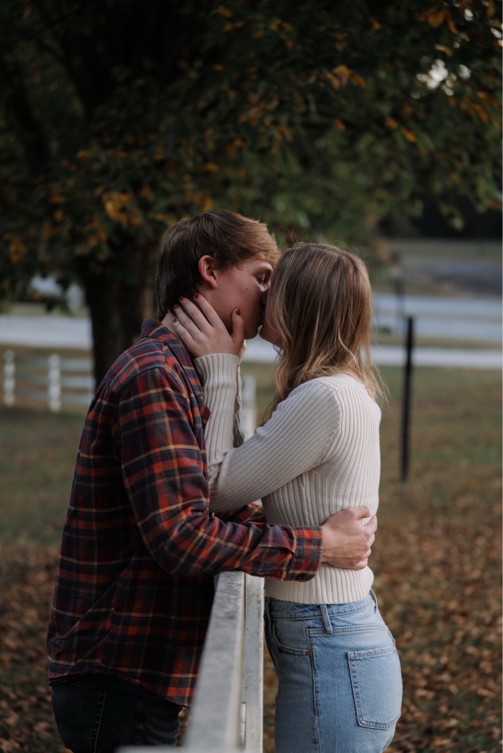 Couple kissing at a fence in autumn