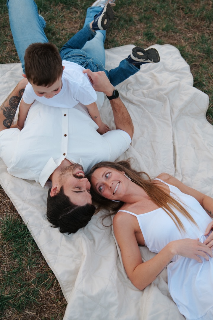 Family of three laying on a blanket in the grass