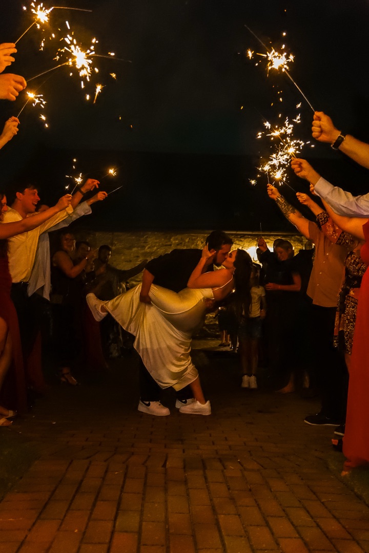 Couple dip kiss under sparklers at wedding reception